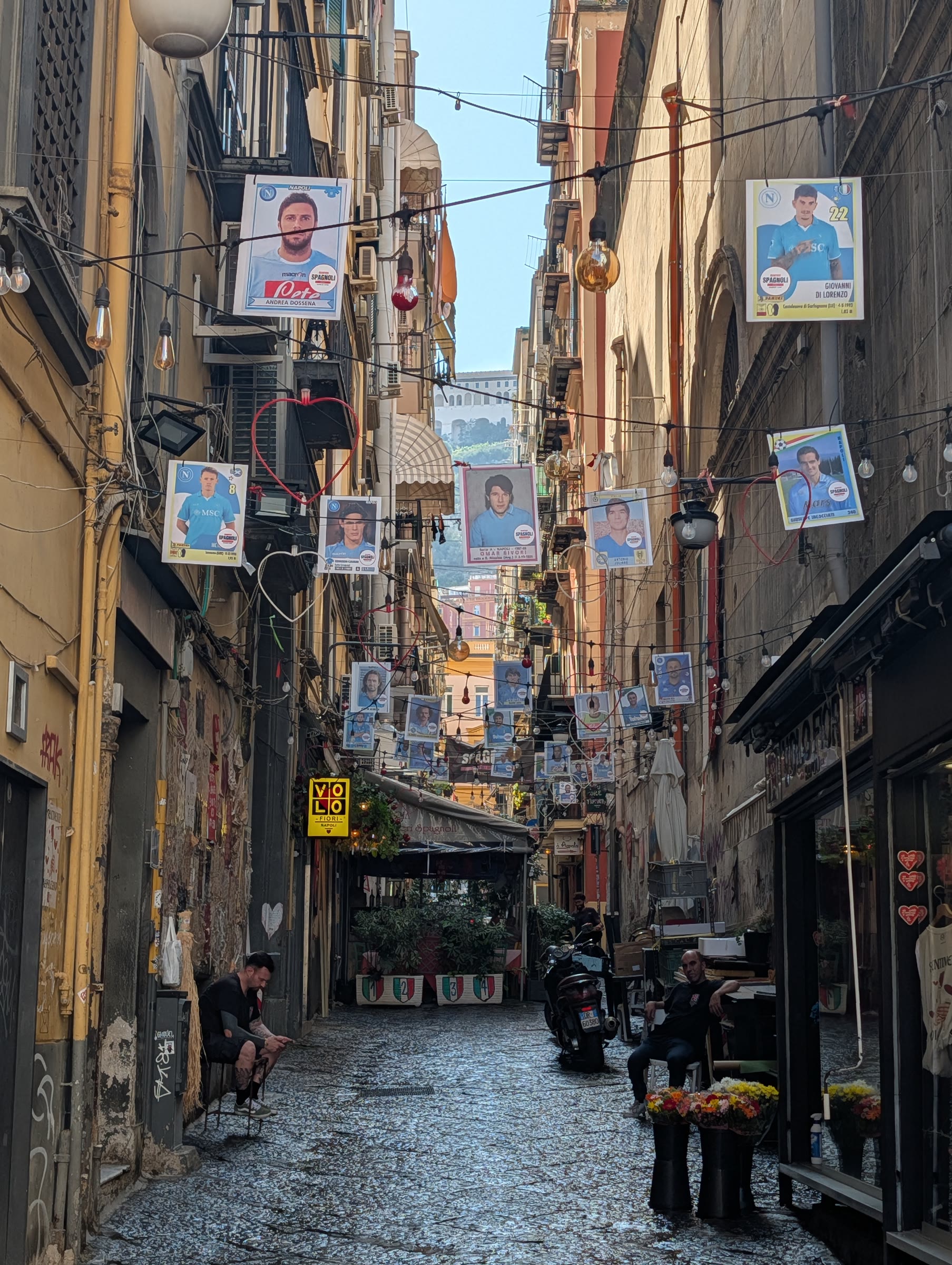 Calle estrecha de Nápoles decorada con banderines y retratos